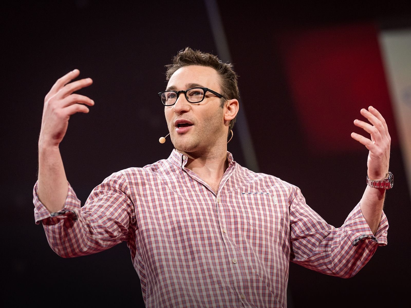 Simon Sinek explicando con las manos en alto en un escenario